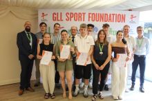 A group of athletes pose with certificates with the mayor