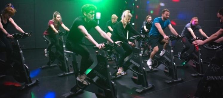 A group of people in a Group Cycle fitness class using static bikes