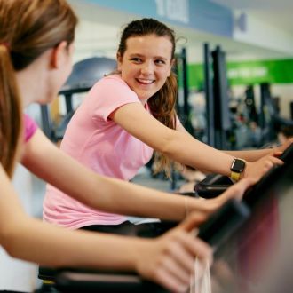 A pair of happy teenage girls working out on treadmills