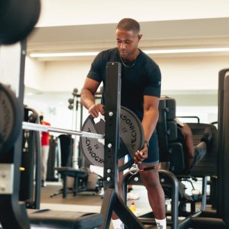 An image of a member putting a plate onto a barbell