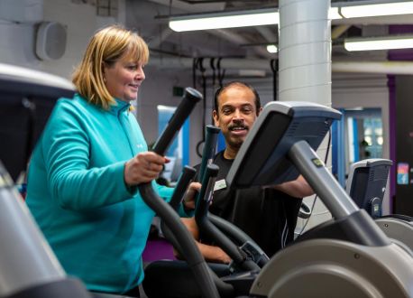 lady on gym equipment with trainer