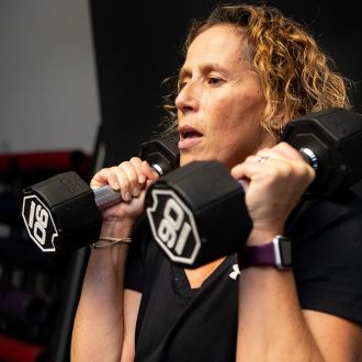 close up of a women's face lifting two dumbells