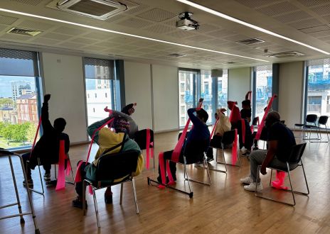 photo taken from behind of a group of older people doing chair yoga