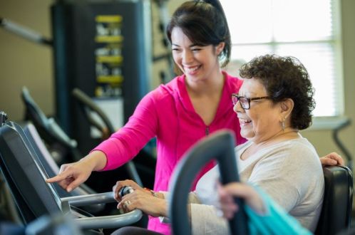Instructor showing lady correct use of exercise equipment