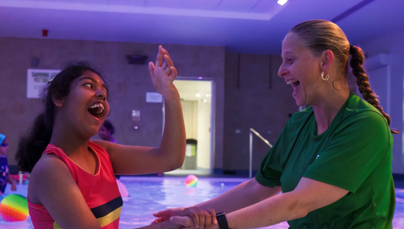 photo of a young girl playing in the water with a staff member