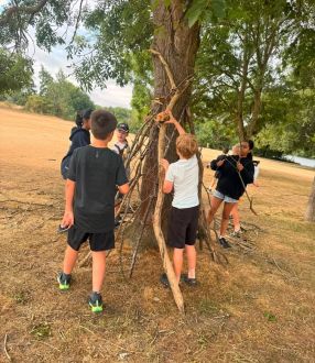 children building a shelter by a tree
