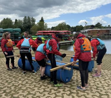 Team of adults building a raft to take on the lake