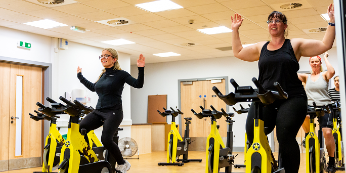 People taking part in a group cycle class on indoor exercise bikes People taking part in a group cycle class on indoor exercise bikes