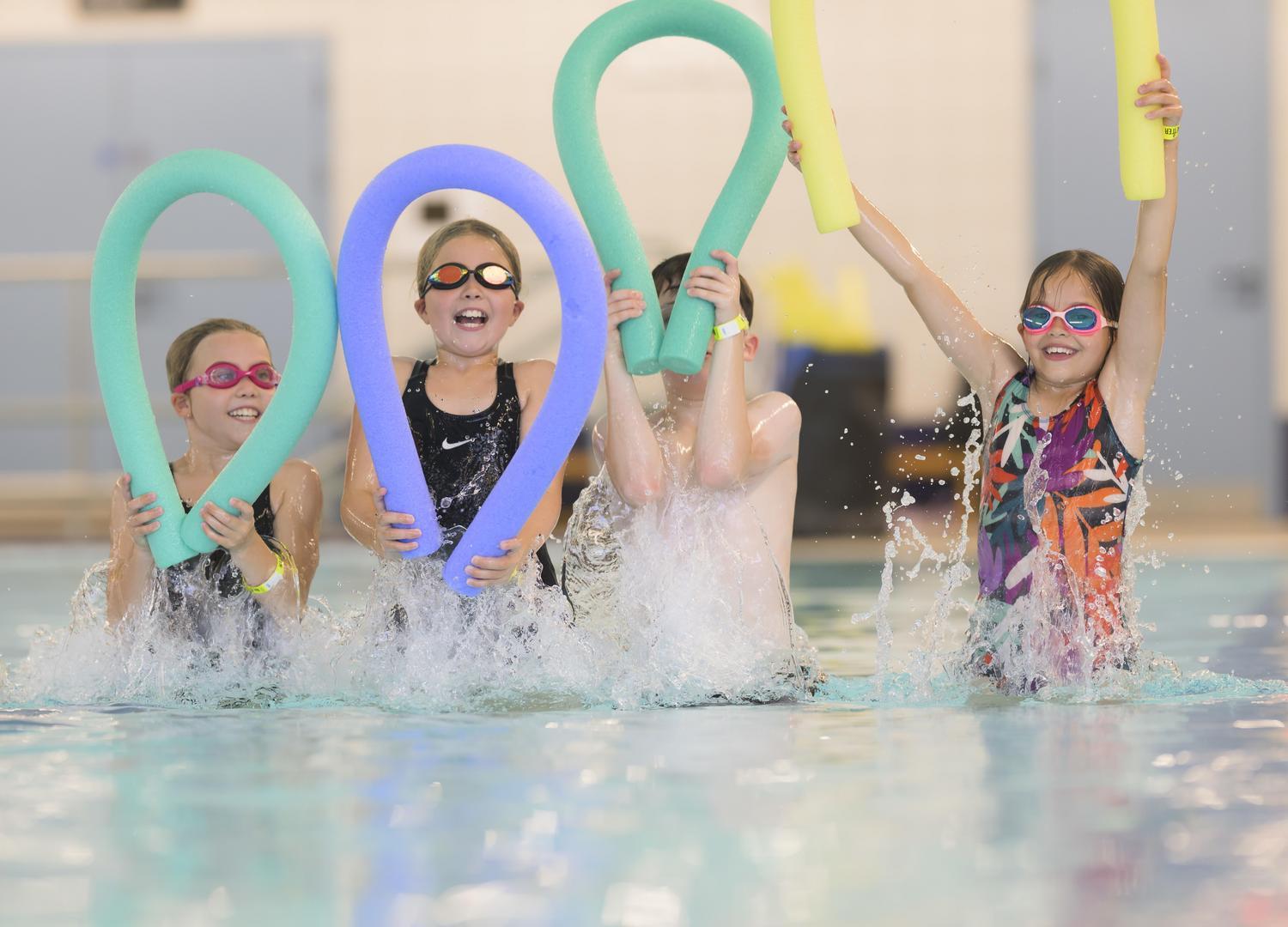children with pool floats splashing in a pool