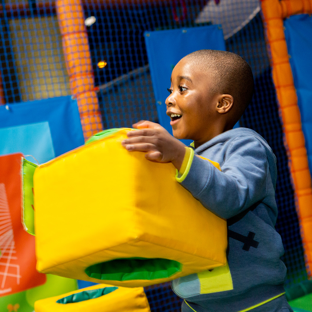 image shows a child in a brightly coloured soft play area