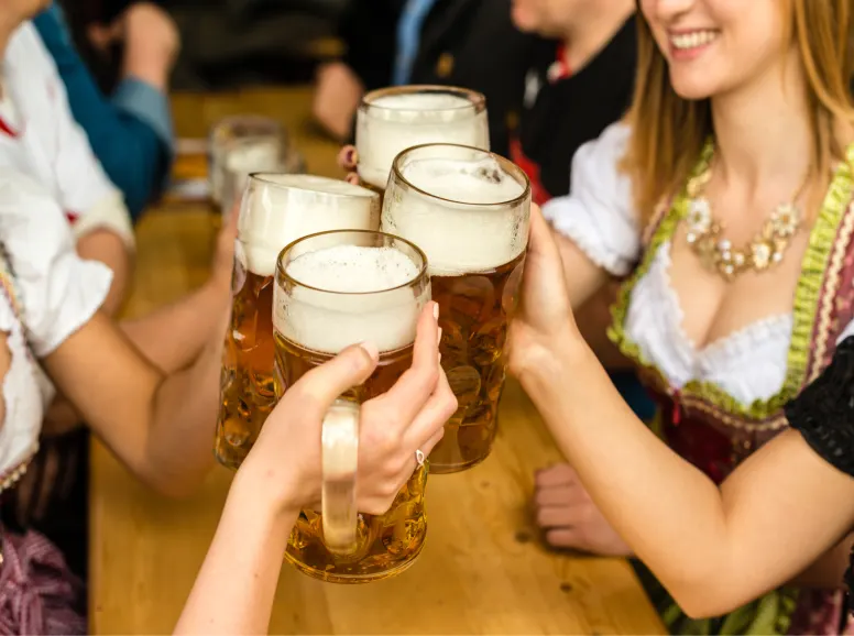 People in Traditional Drindl Costumes Toasting at a Bavarian Bar