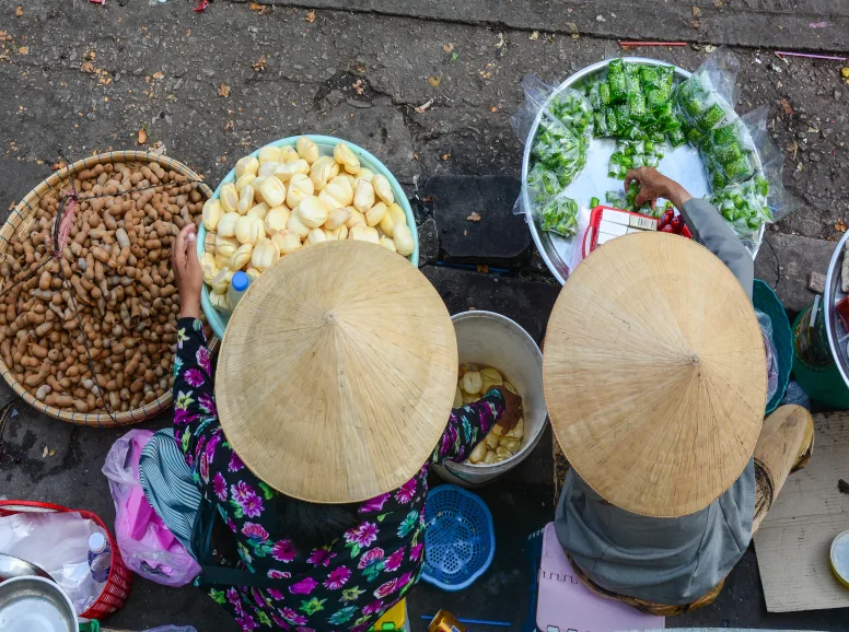 women with conical hats serving bowls of food