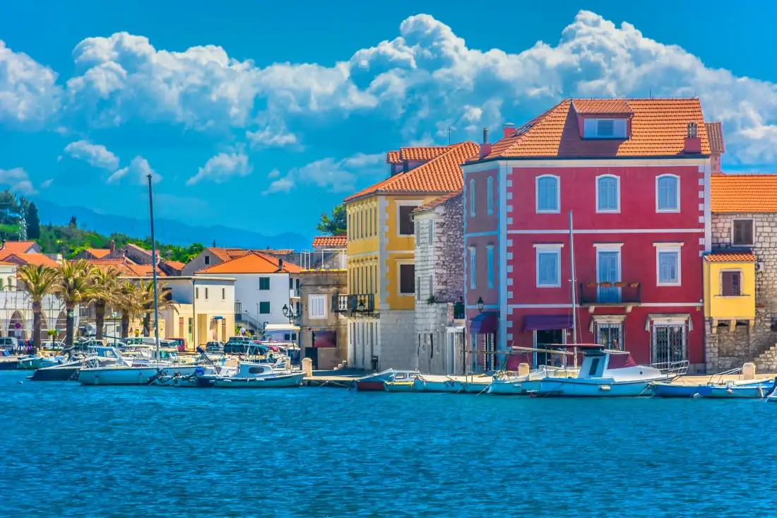 waterfront with colourful houses and fluffy clouds