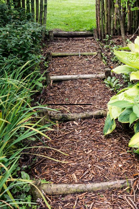 Eine Knüppeltreppe mit Naturmaterialien wirkt im Naturgarten besonders