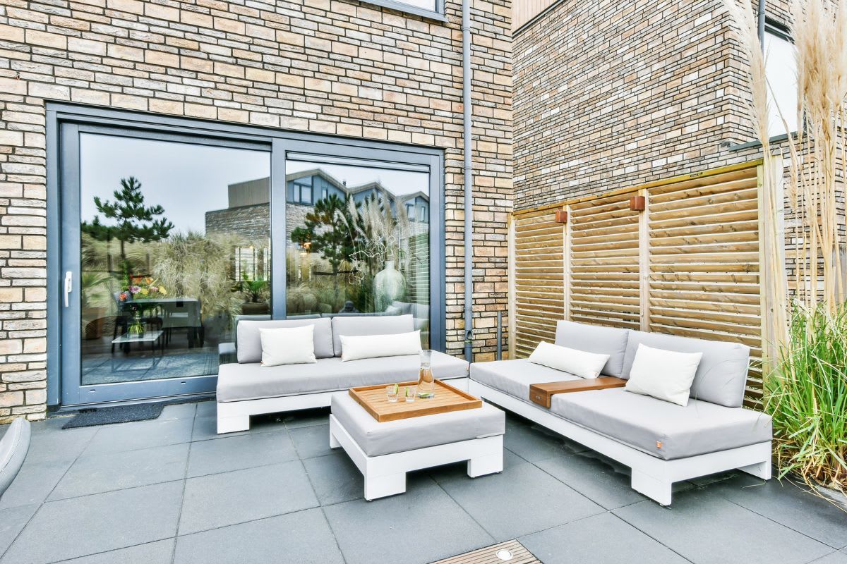 Gepflegte Terrasse mit modernen Gartenmöbeln auf sauberen Terrassenplatten, einladend für entspannte Stunden mit Familie und Freunden im Sommer.