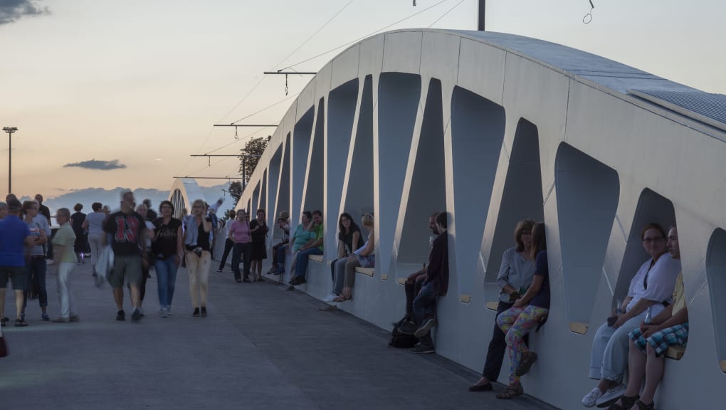 View of people walking across the Kienslesberg Bridge as the sun sets