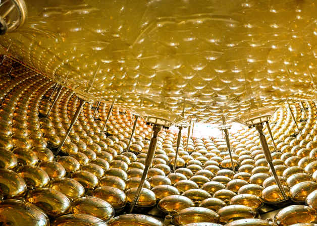 Interior view of a room filled with numerous golden, reflective spheres covering the walls and ceiling.