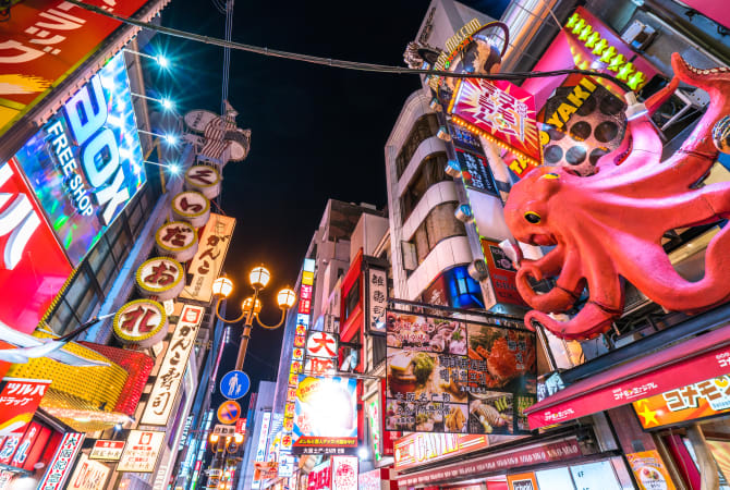 a street at night with neon signs and an octopus model
