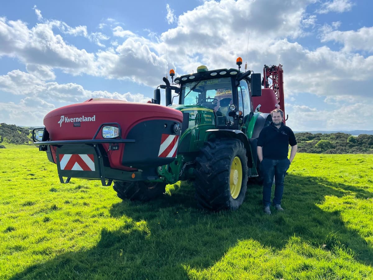 Jack Wilson står framför sin Kverneland iXter B monterad på sin John Deere-traktor