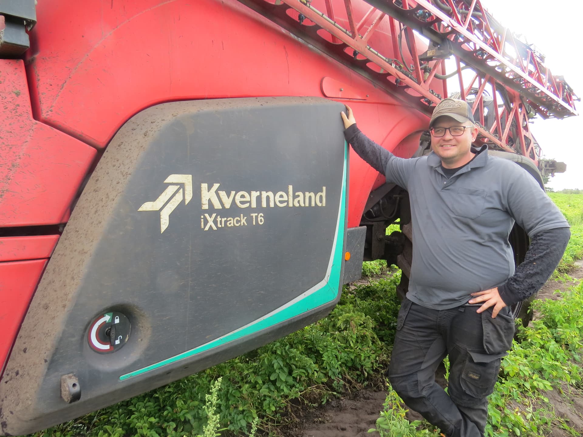 Simon Bækgaard Christensen standing beside his Kverneland iXtrack T6 field sprayer in Denmark.