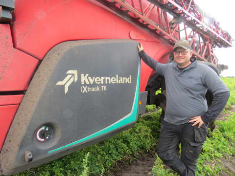 Simon Bækgaard Christensen standing beside his Kverneland iXtrack T6 field sprayer in Denmark.