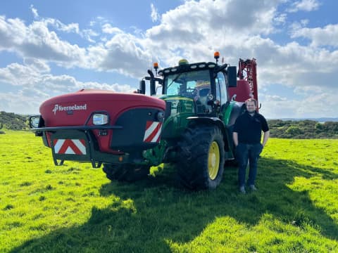 Jack Wilson standing in front of his Kverneland iXter B mounted on his John Deere tractor