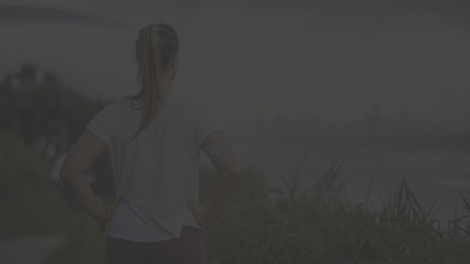 someone with a continuous glucose monitor on their arm while on a jog in nature 