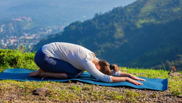 child pose woman doing yoga outside