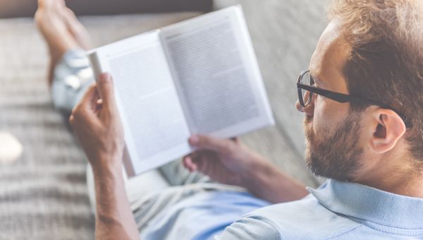 man reading a book on couch