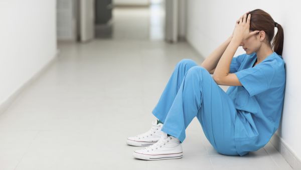 nurse tired sitting up against wall