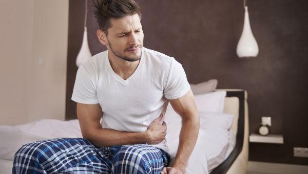 man on bed with stomach pain