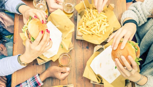 Group of friends toasting beer glasses and eating at fast food - Happy people partying and eating in home garden - Young active adults in a picnic area with burgers and drinks