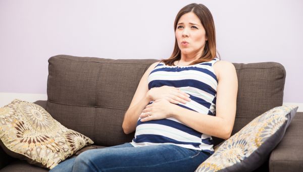 pregnant person holding belly and breathing deeply