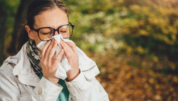 woman sneezing in fall