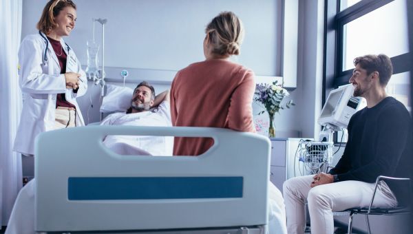 Patient lying in hospital bed surrounded by family