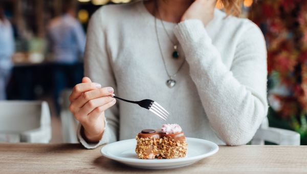 someone eating dessert, cake, fork, sweater, restaurant