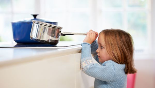 young girl holding cooking pot, kitchen dangers for children