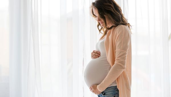 pregnant woman, holding pregnant belly, window, white curtains