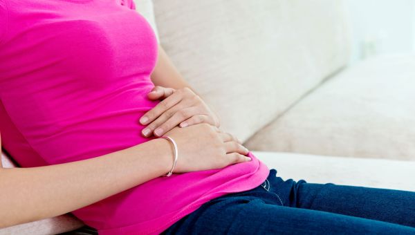 woman holding her stomach, stomach ache, couch