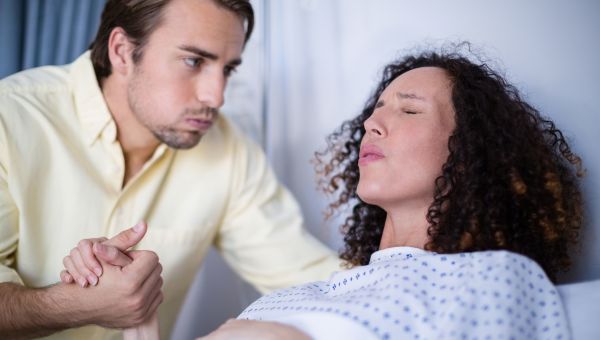 someone giving birth, holding another person's hand while giving birth