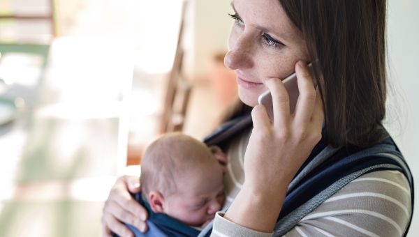 Someone talking on mobile phone while holding newborn