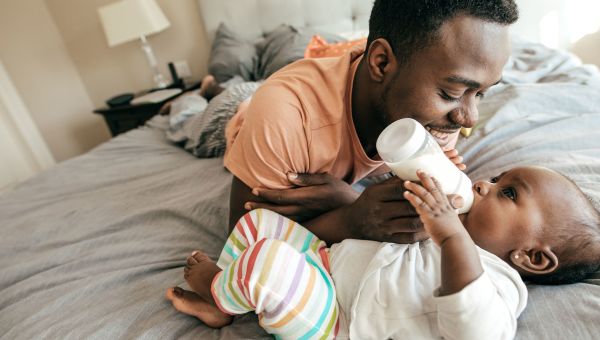 Father feeding baby with milk from bottle