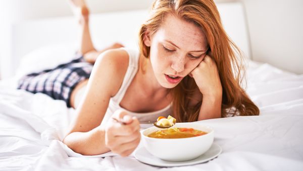 woman eating soup in bed