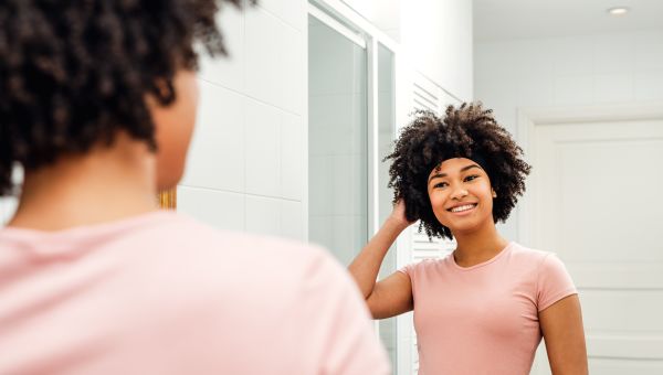 young black woman looking in mirror