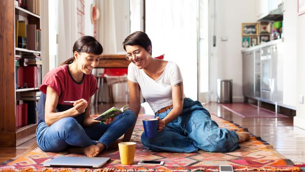 lesbian couple sits on rug on floor, happily talking