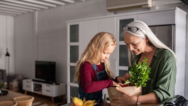 an elderly woman and grand daughter unpack healthy groceries in a kitchen