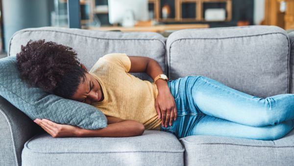 person clutching belly, lying on couch