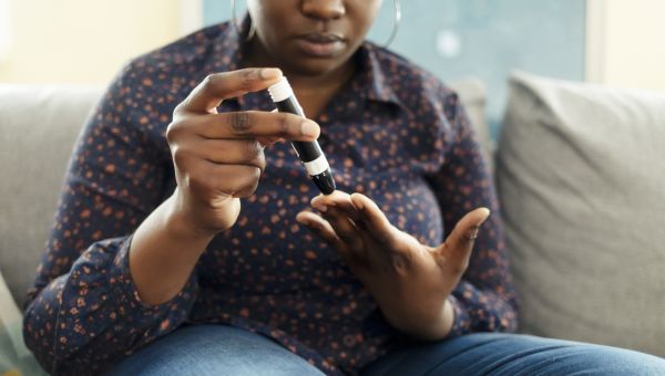a Black woman checks her blood sugar levels 