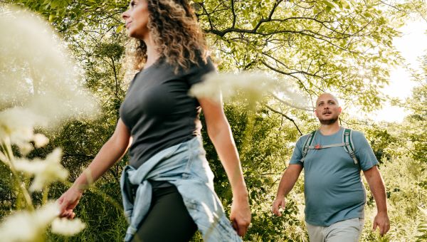 an overweight white man and his wife hike in the woods