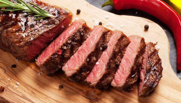 Sliced steak on a wooden cutting board.